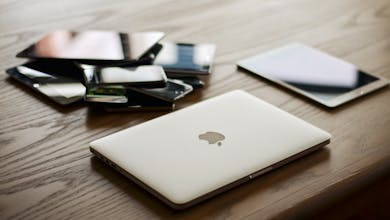 A variety of modern electronic gadgets, including a laptop and smartphones, on a wooden table.