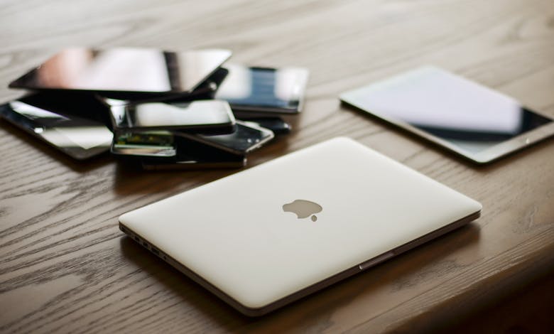 A variety of modern electronic gadgets, including a laptop and smartphones, on a wooden table.