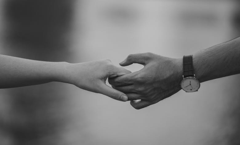 Monochrome image of two hands holding, symbolizing love and connection.