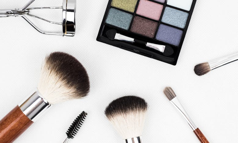 Top view of makeup tools and a colorful eyeshadow palette arranged artistically.