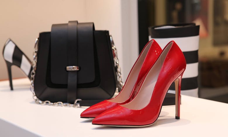 Showcasing sleek red stilettos and a chic black handbag in a luxury boutique setting.