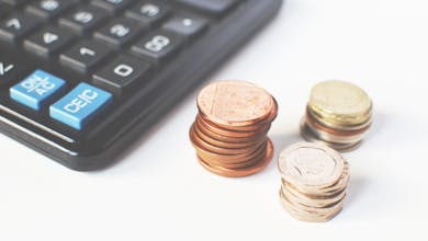 Close-up of stacked coins and a calculator symbolizing financial strategy and budgeting.