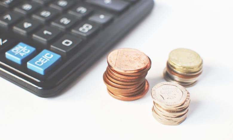 Close-up of stacked coins and a calculator symbolizing financial strategy and budgeting.